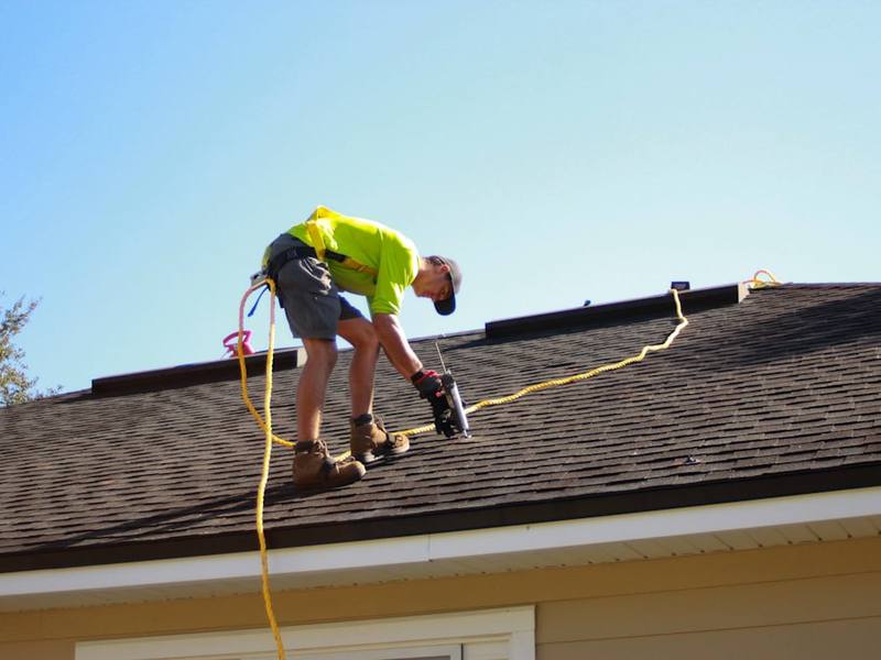 Roofer nailing shingles on a new roof